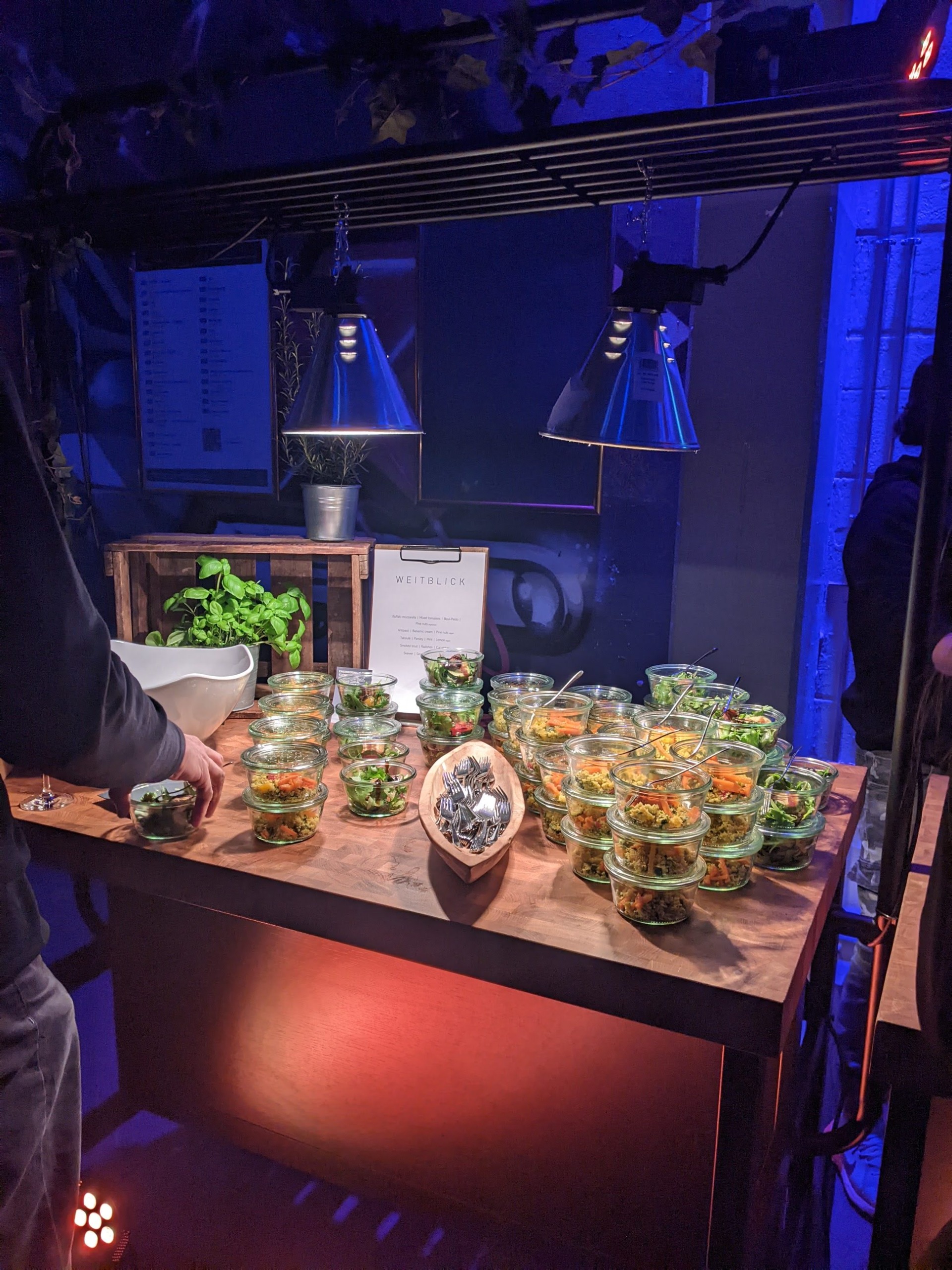 Blue-lit dessert buffet with layered displays and floral accents.