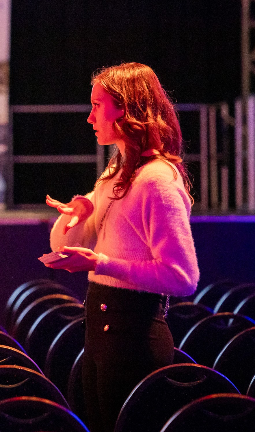 Event team briefing inside a venue with layered seating and stage lighting.